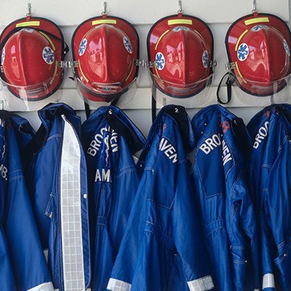 closeup of fire fighter's helmets and fire protective suits haning on hooks
